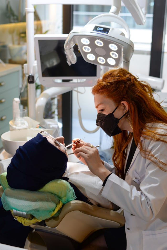 Home A female dentist with red hair treating a patient in a dental clinic. Professional healthcare setting.